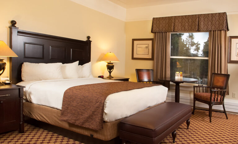 Neatly made bed with white pillows, bedside lamps and a window in a calm bedroom