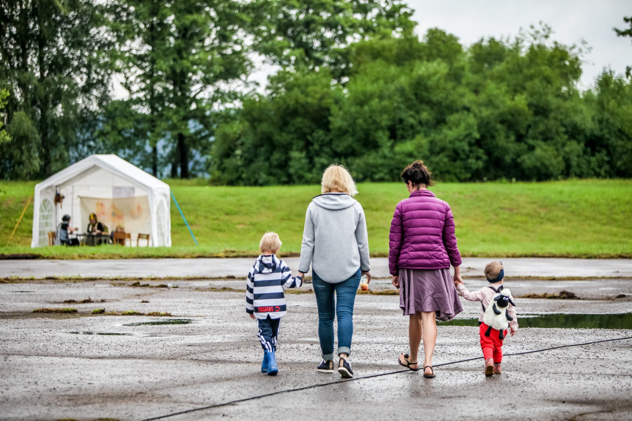 Two women and two small children walking hand in hand across a wet park path