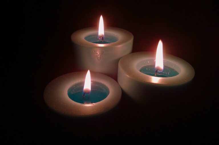 Three lit candles glowing softly in a dark room for a calm evening