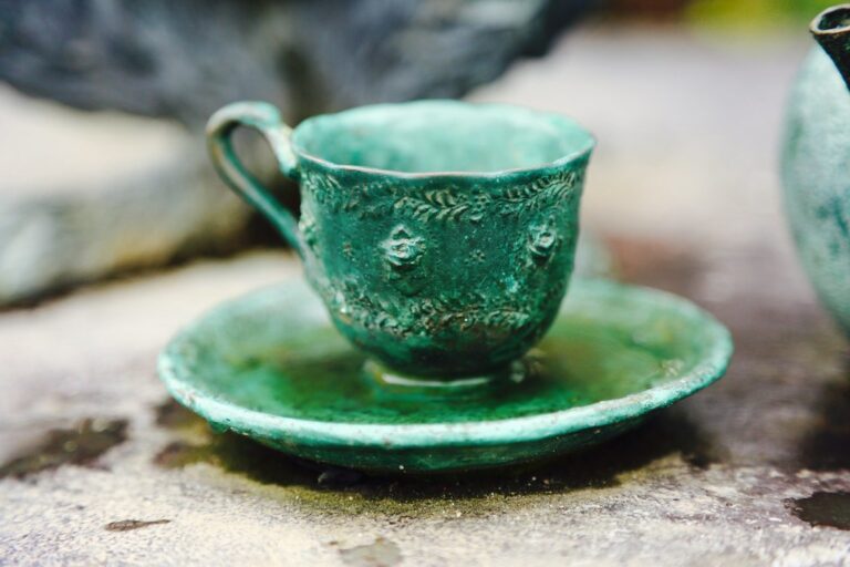 Green ceramic teacup on a matching saucer resting on a stone surface