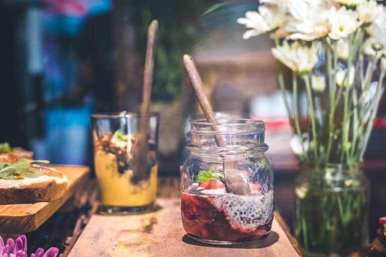 Glass jars of chia pudding with berries and yogurt on a wooden table