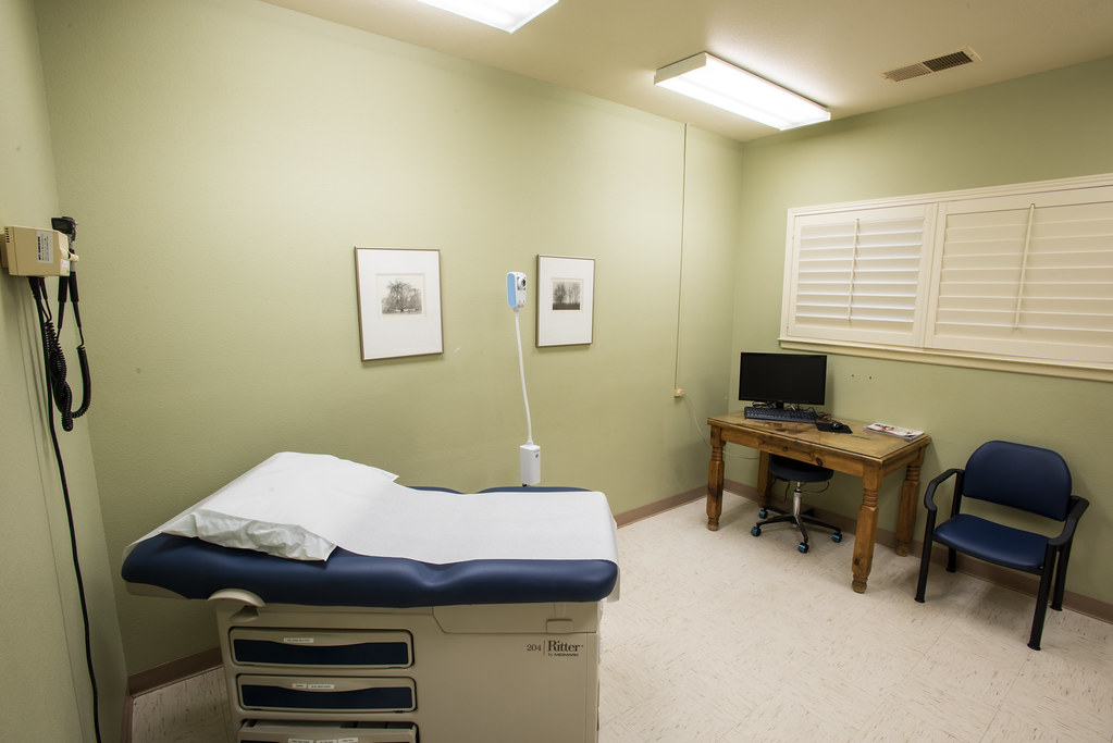 Clean, quiet clinic examination room with a padded exam table and chair