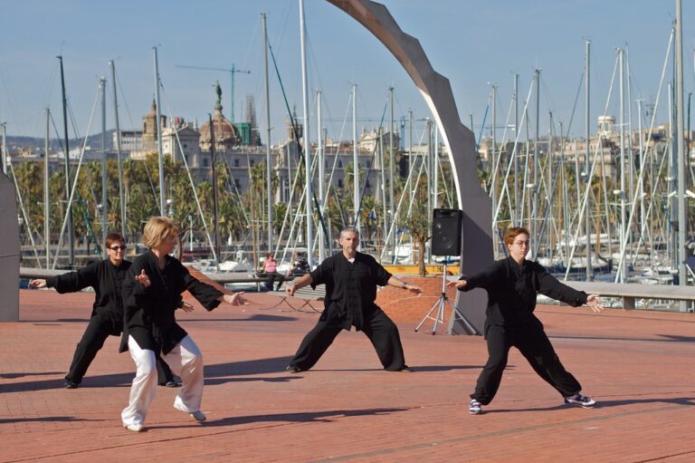 Three people practicing slow tai chi moves on a sunny harbor square