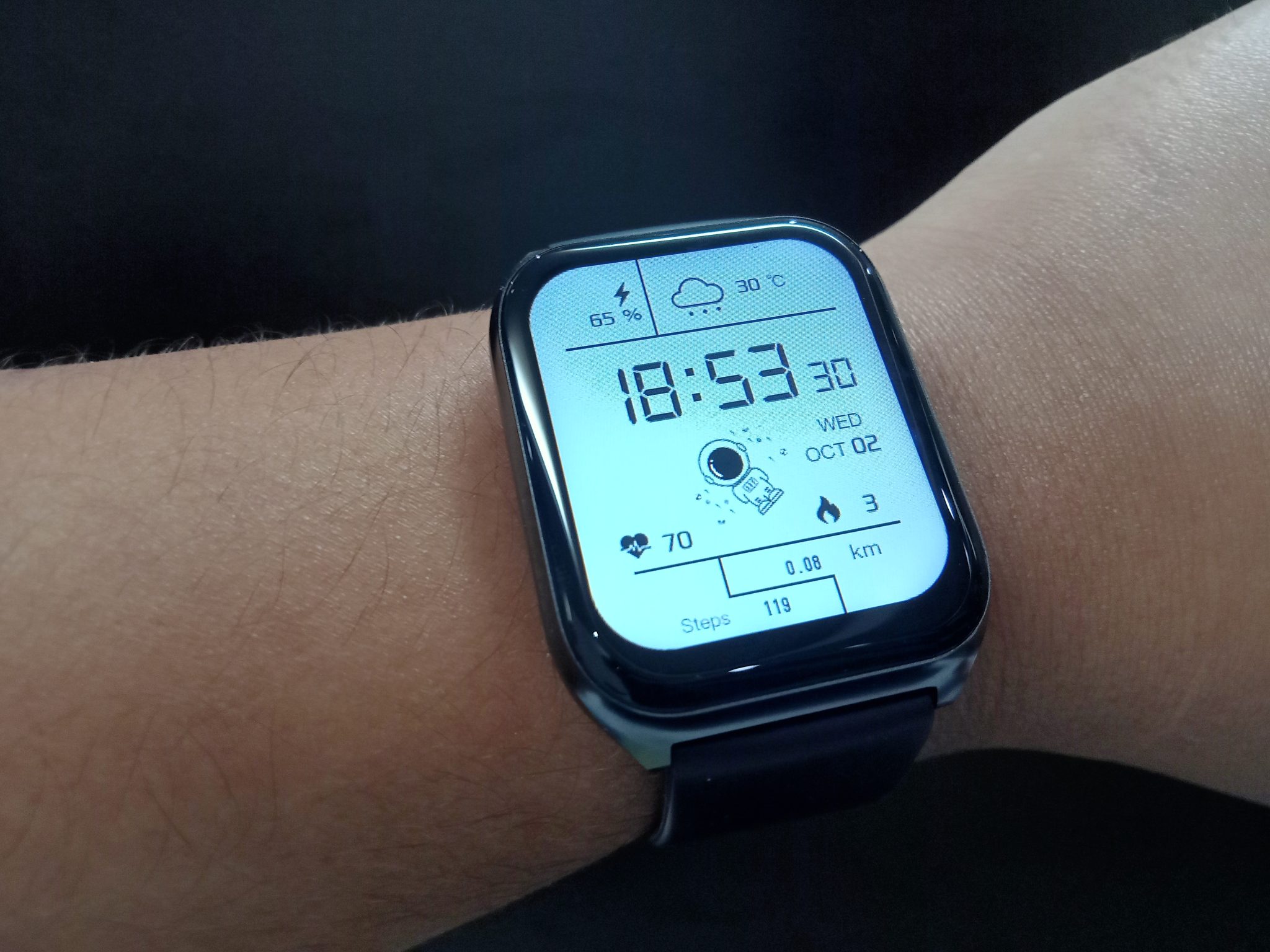 Close-up of a smartwatch on a wrist showing the time, steps and heart rate