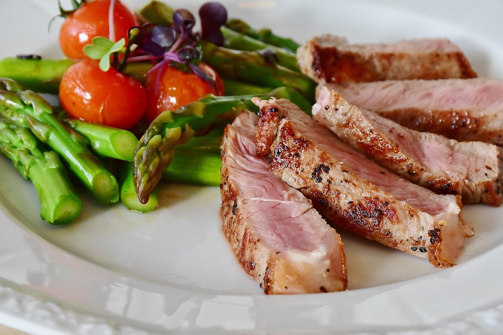 Plate of sliced grilled steak with green asparagus and cherry tomatoes