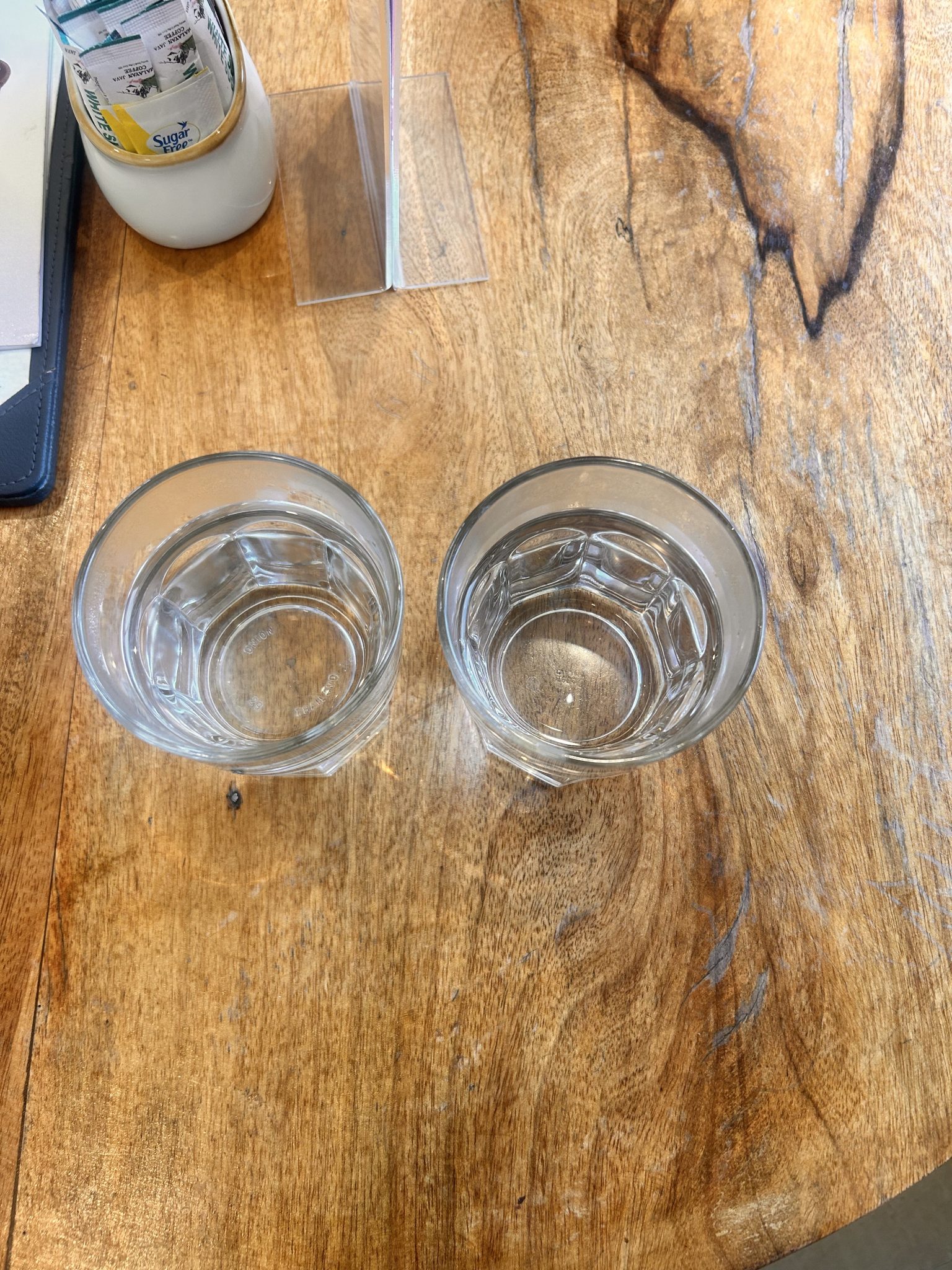 Two clear glasses of drinking water sitting on a rustic wooden table