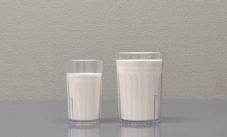 Two clear glasses of fresh white milk standing side by side on a table