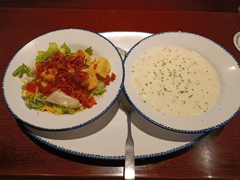 A small bowl of creamy soup next to a side salad on a wooden table