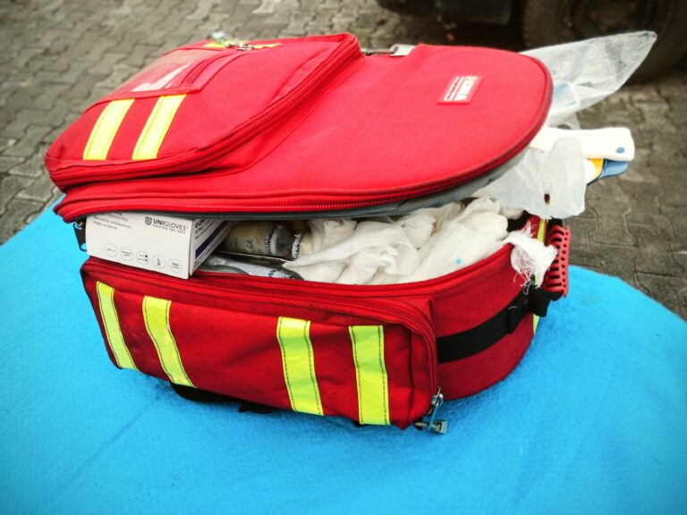 Open red first aid bag with reflective stripes, packed with medical supplies