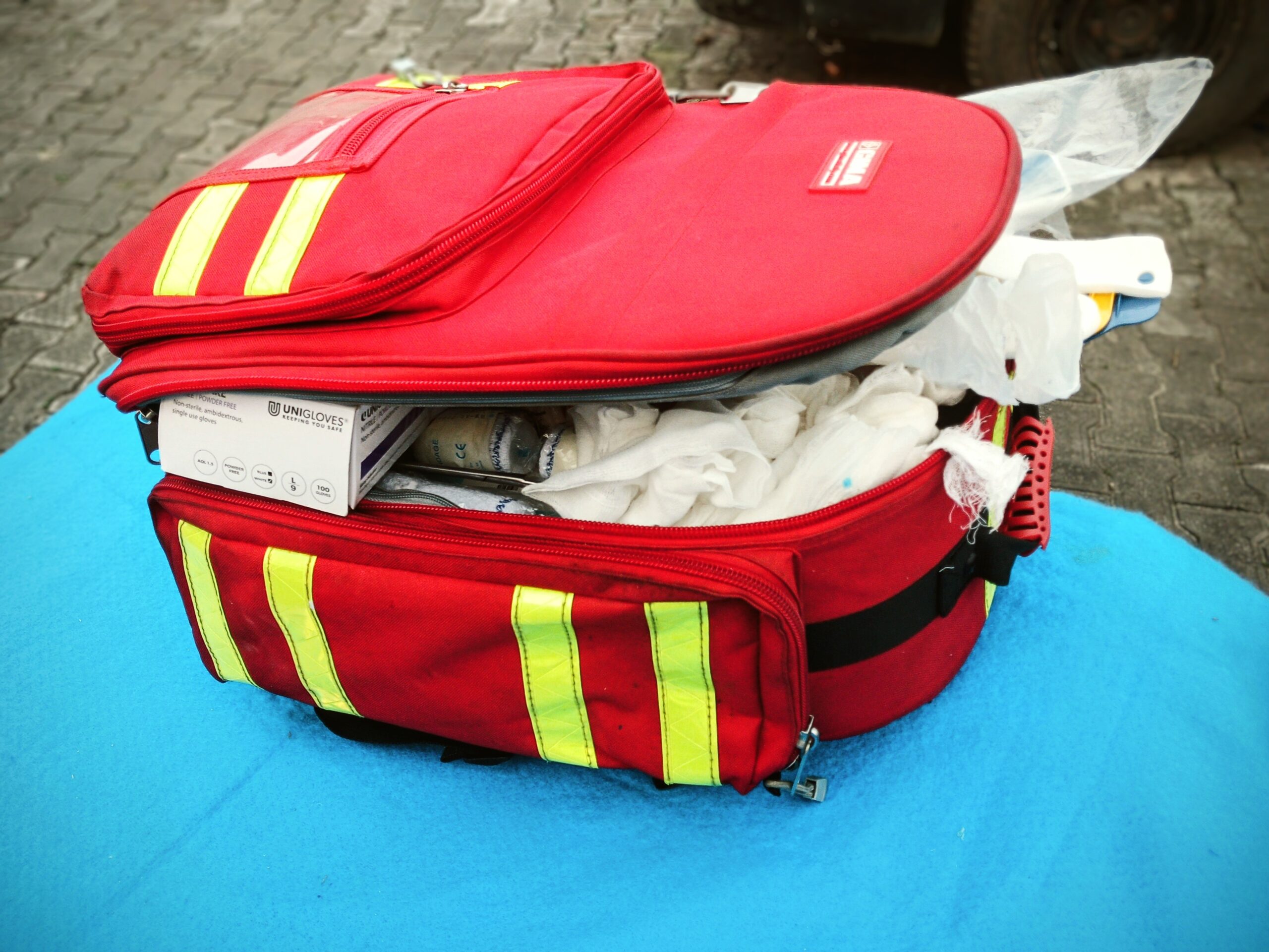 Open red first aid bag with reflective stripes, packed with medical supplies