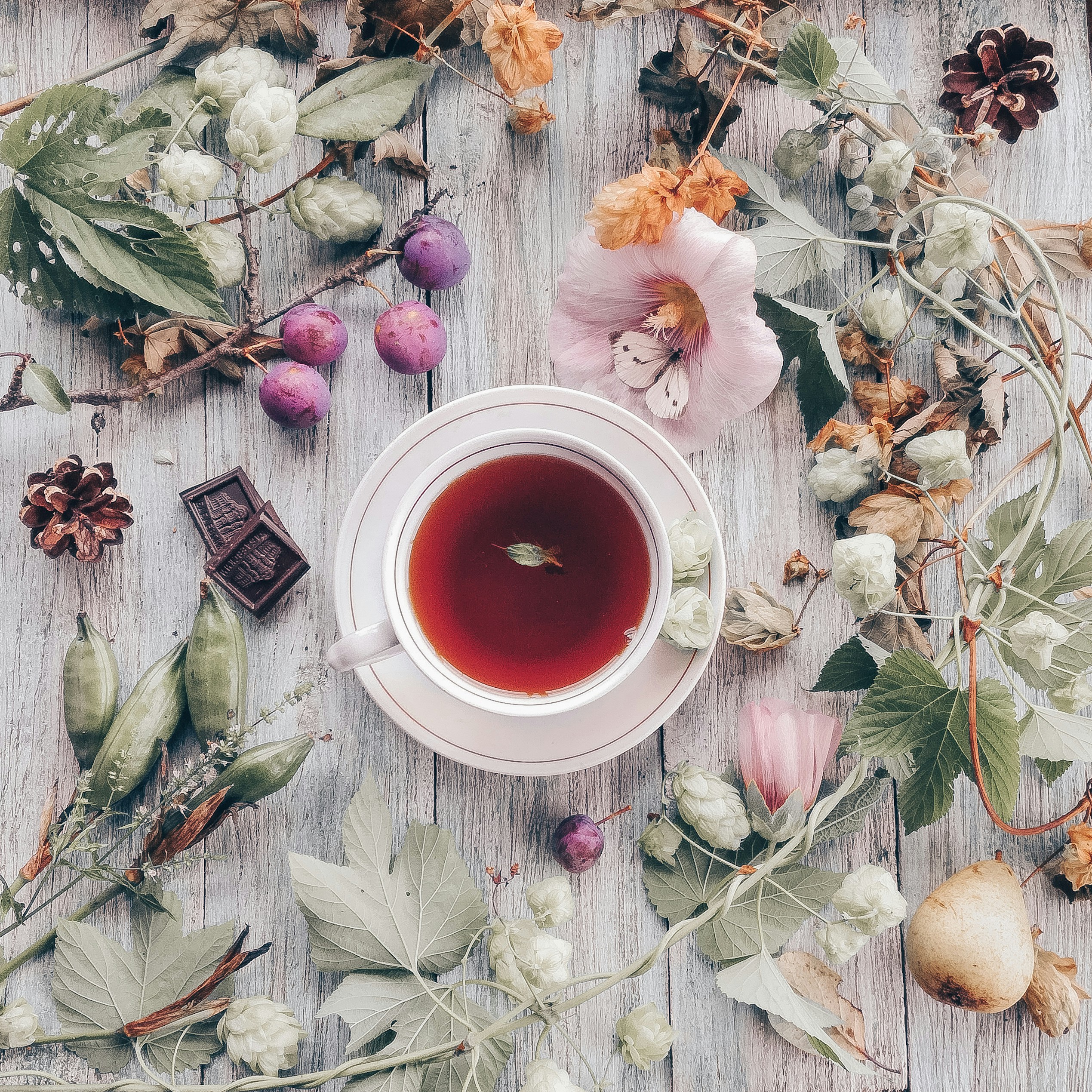 Open book and a mug of tea on a small table beside a warm fireplace