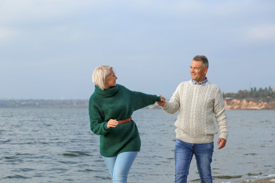 Happy senior couple walking hand in hand on a sunny beach